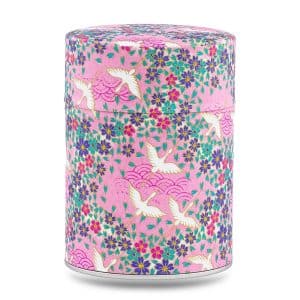 Boîte à thé artisanale Masuda 100 g, recouverte de papier washi rose orné de grues blanches et de petites fleurs violettes, couvercle assorti décoré.